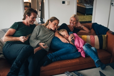 Family relaxing on the sofa with their mobile phones