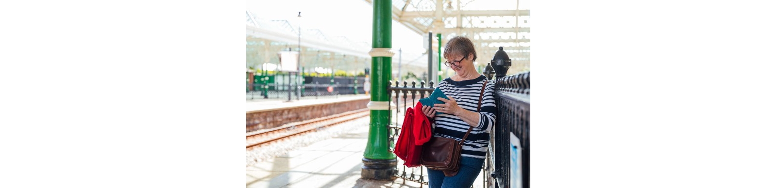Lady smiling at her phone on a train station
