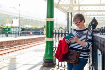 Lady smiling at her phone on a train station